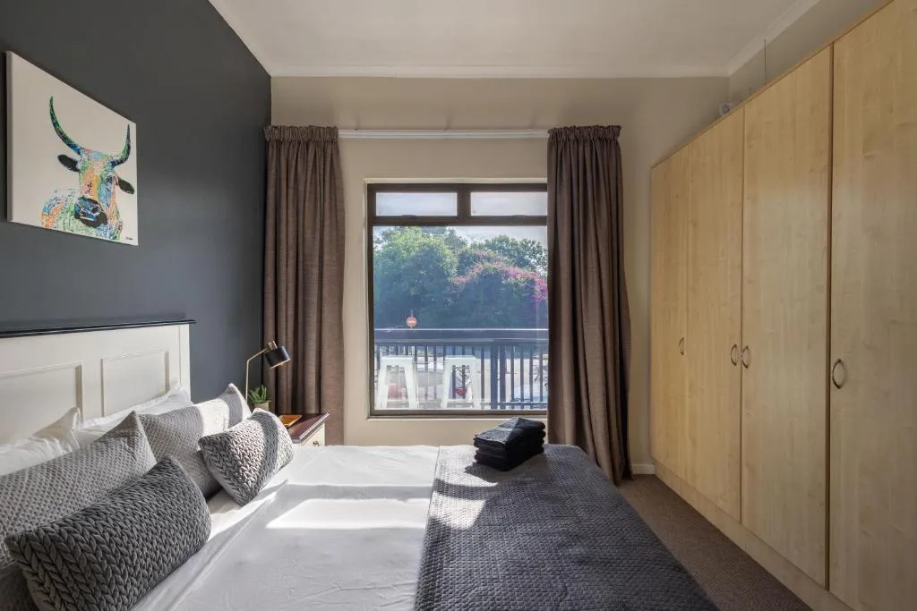 Bright bedroom with bed, wooden wardrobe, and lagoon view through glass doors