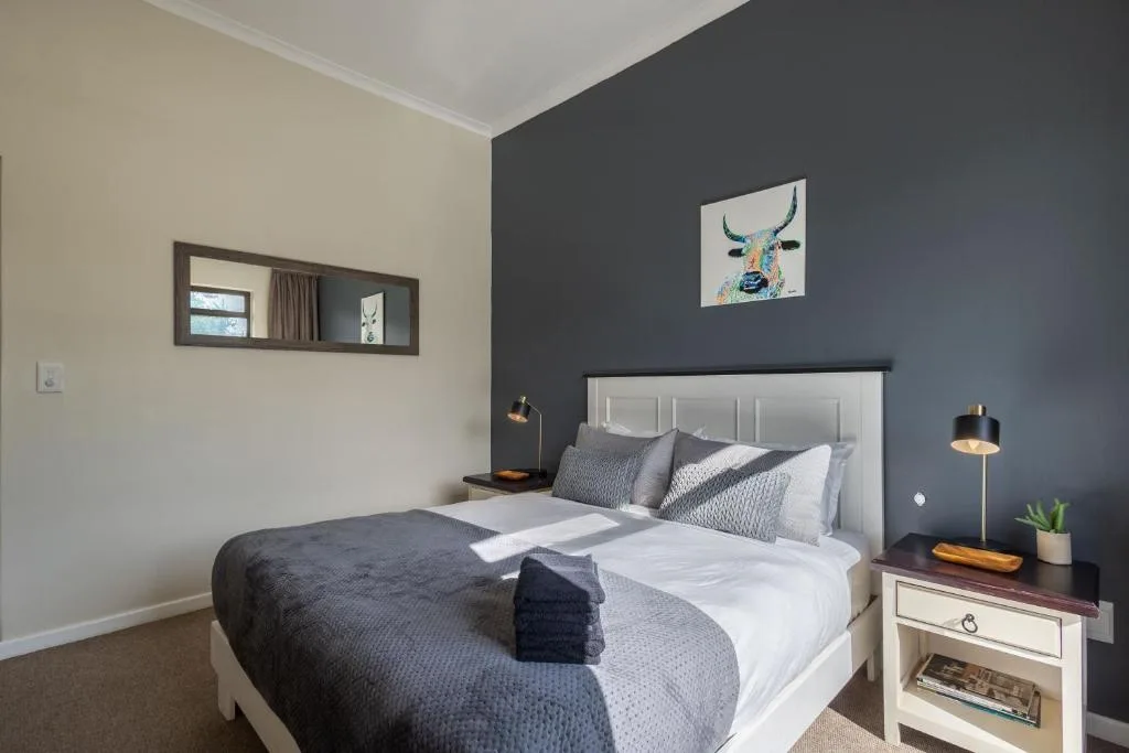 Modern bedroom with bed, dark accent wall, bedside lamps, and artwork