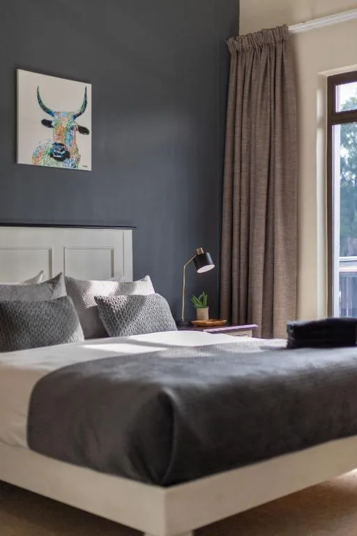 Modern bedroom with white bed frame, dark grey walls, and colorful bull artwork