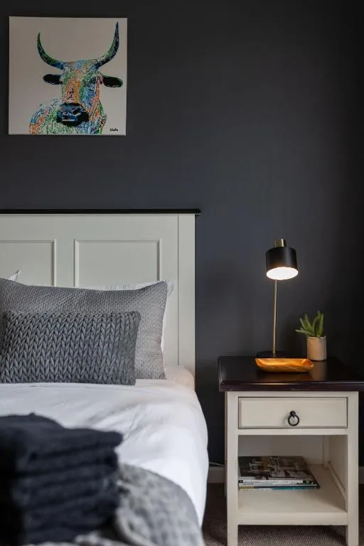 Modern bedroom with colorful bull artwork, gray bedding, and pendant lamp