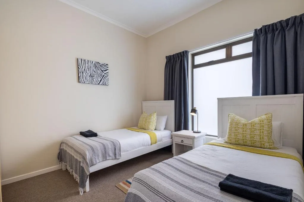 Bright bedroom with two single beds and yellow accent pillows