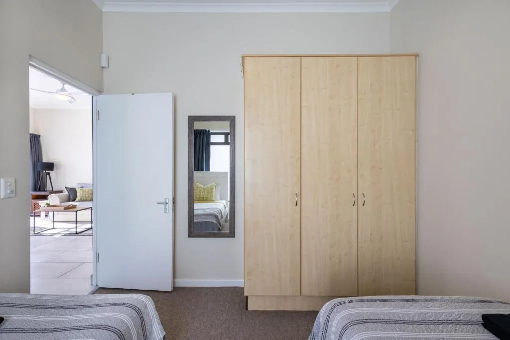 Spacious bedroom with twin beds and light wood wardrobe storage