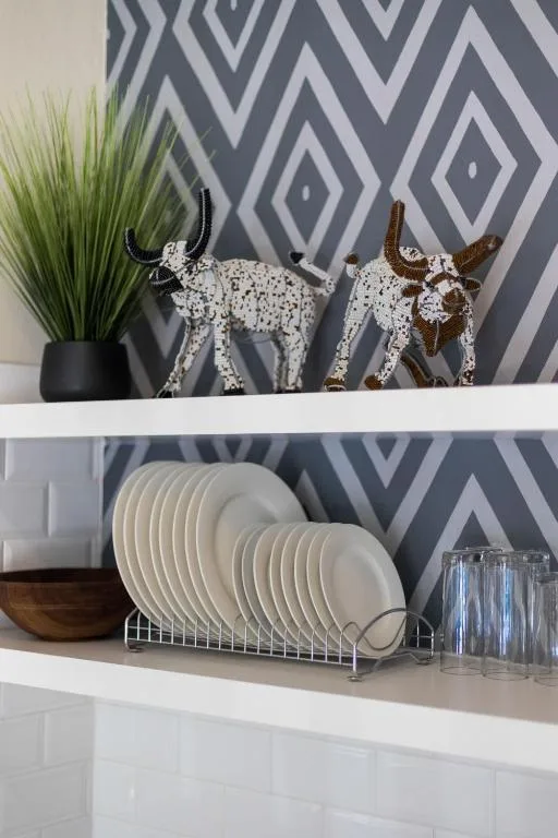 Decorative shelf with geometric wallpaper, ceramic plates, and ornamental cow figurines
