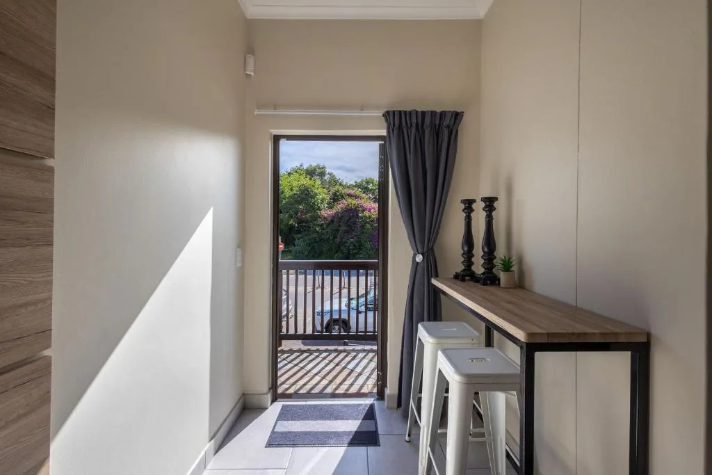 Modern hallway with desk, stools, and glass door opening to garden views