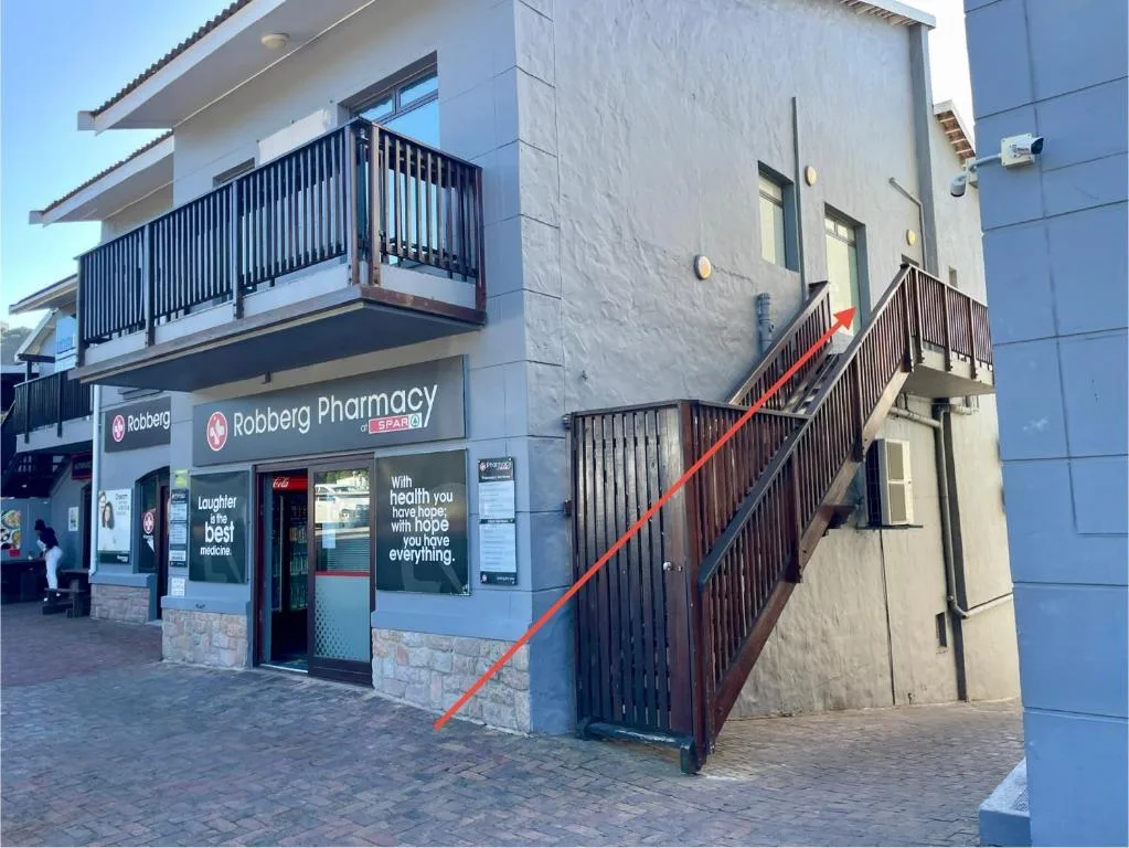 Modern building facade with balconies and ground-floor pharmacy storefront