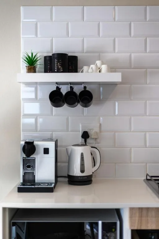 Modern kitchen shelving with white subway tiles, kettle, coffee maker, and cookware