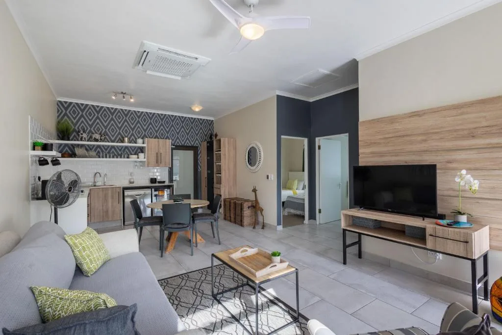 Modern open-plan lounge with sofa, TV, and integrated kitchen area