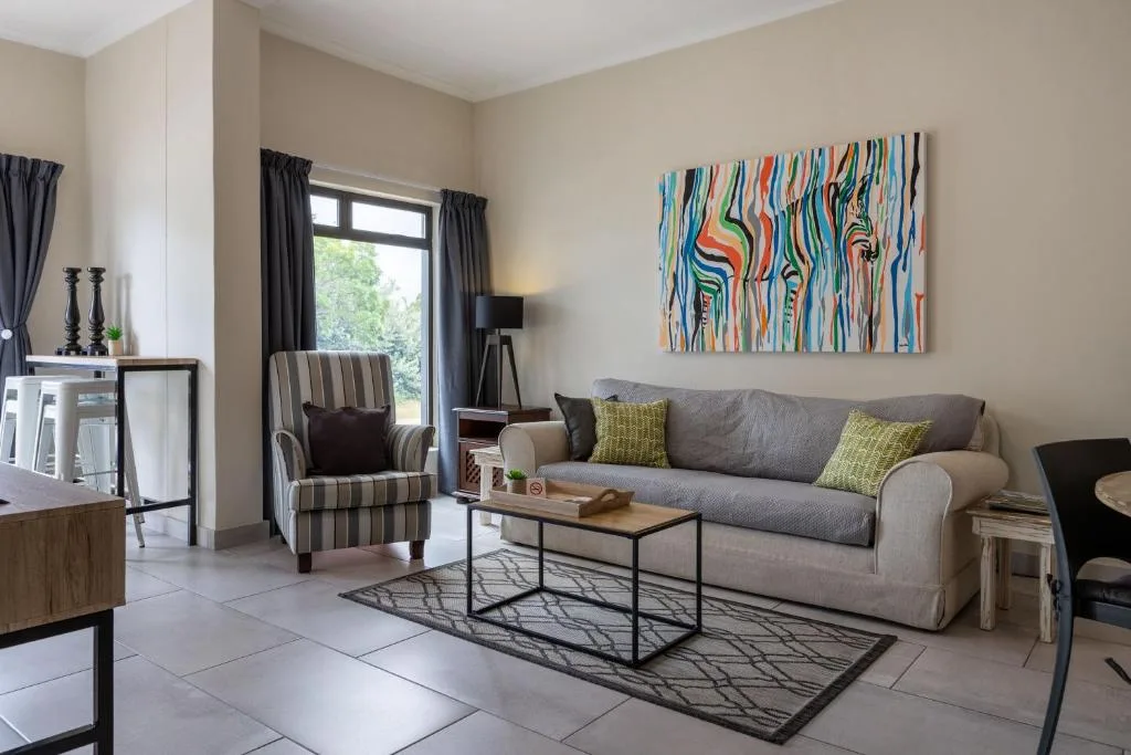 Modern lounge with gray sofa, striped armchair, and vibrant abstract artwork