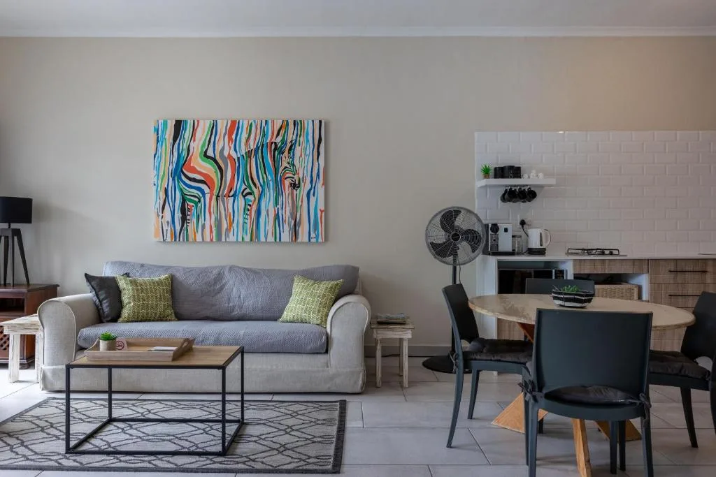 Open-plan living area with gray sofa, colorful wall art, and dining space