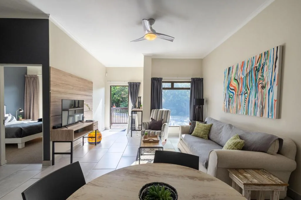 Spacious open-plan lounge with gray sofa, TV, and colorful abstract artwork