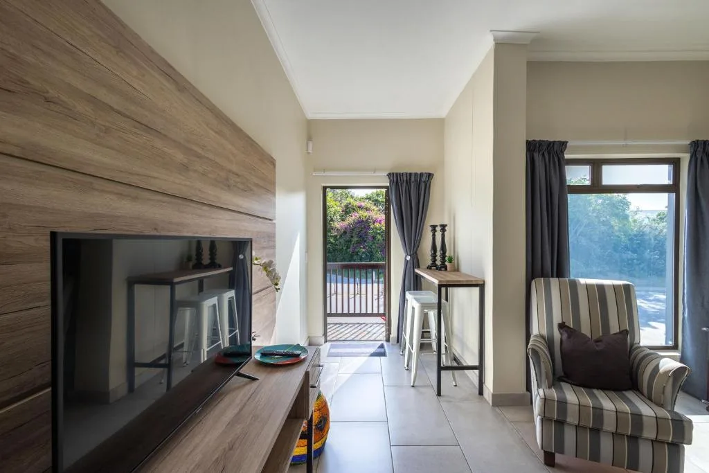 Modern lounge with striped armchair, TV, and glass doors to deck