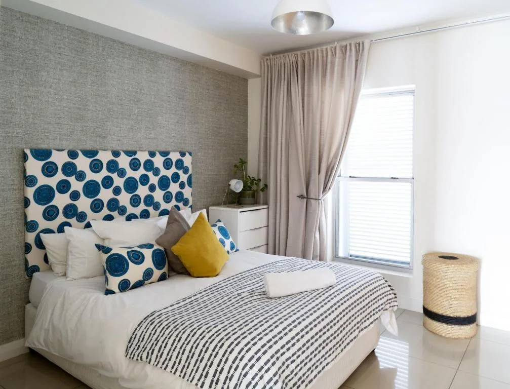 Bright bedroom with patterned headboard and striped bedding, natural light