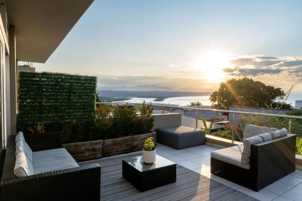Elevated deck with outdoor seating overlooking lagoon and mountains at sunset