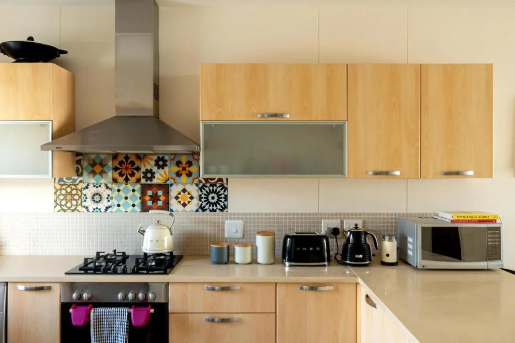 Modern kitchen with wooden cabinetry, patterned tile backsplash, and stainless steel appliances