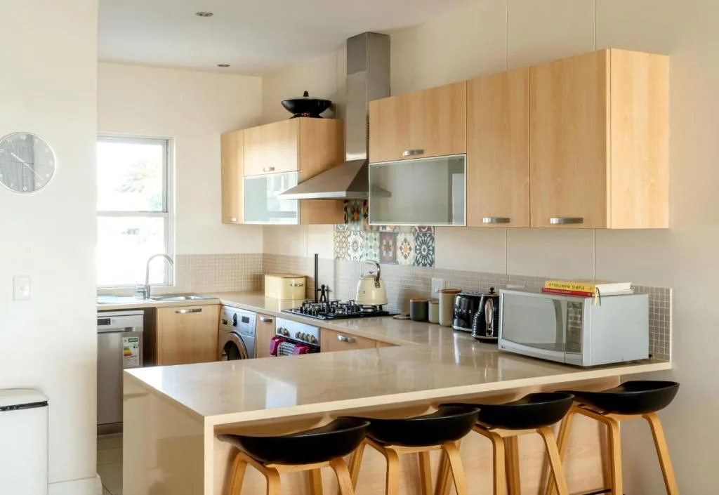 Modern kitchen with wooden cabinetry, island seating, and stainless steel appliances