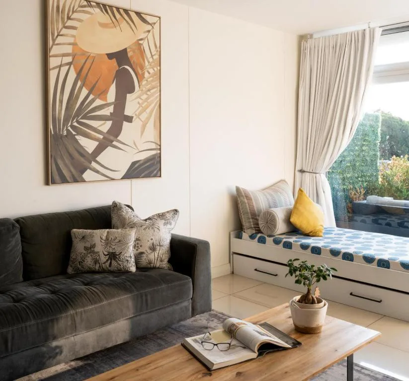 Modern lounge with black sofa, botanical artwork, and garden views through windows