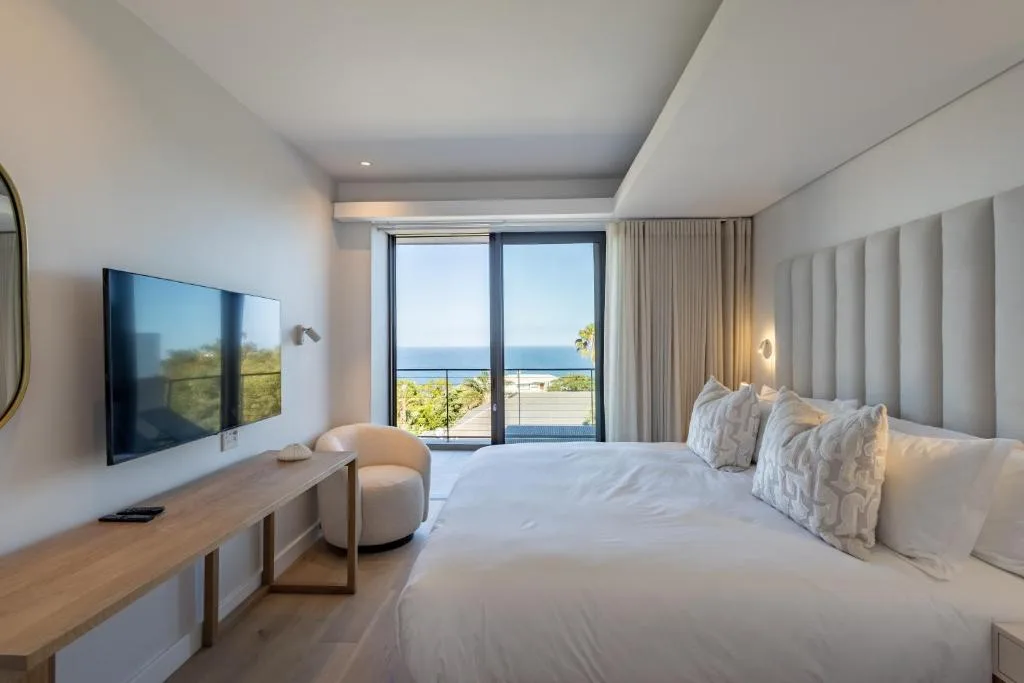 Modern bedroom with ocean views through floor-to-ceiling windows and sliding doors