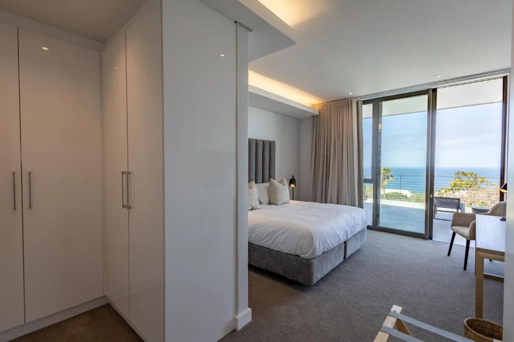 Modern bedroom with ocean view through glass doors and balcony access