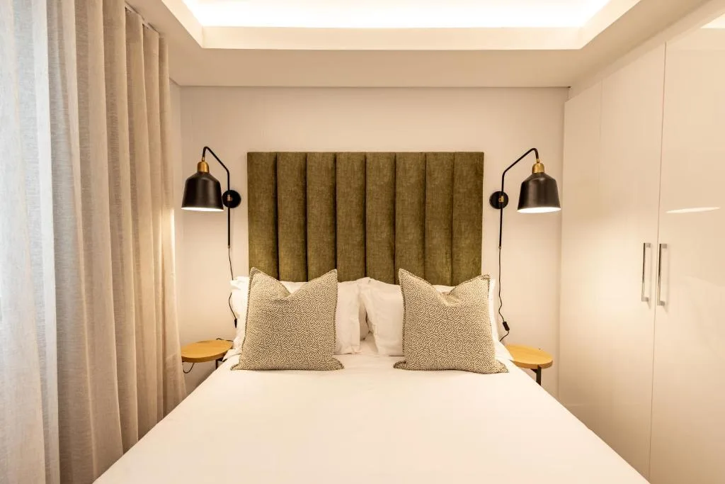 Modern bedroom with upholstered headboard, white bedding, and designer pendant lamps