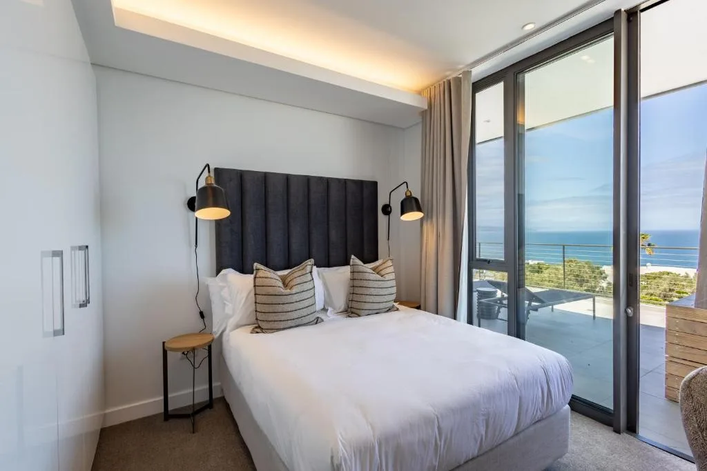 Modern bedroom with ocean view through glass doors and coastal scenery