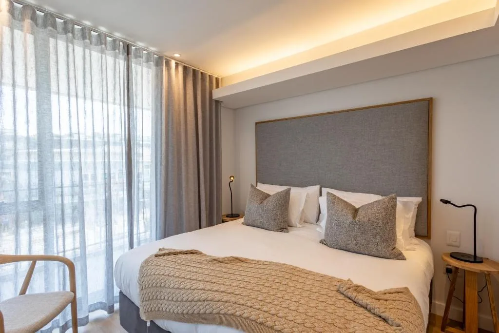 Modern bedroom with queen bed, gray upholstered headboard, and floor-to-ceiling curtains