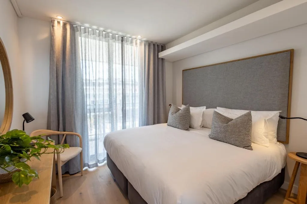 Modern bedroom with queen bed, gray upholstered headboard, and sheer curtains