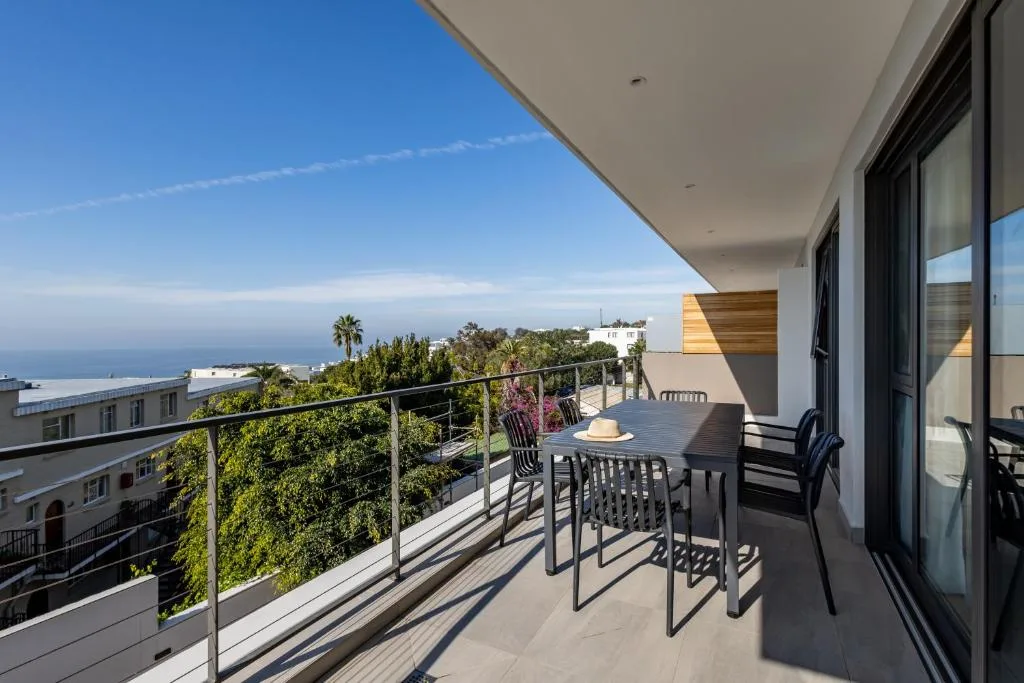 Modern outdoor deck with dining table overlooking ocean and town landscape