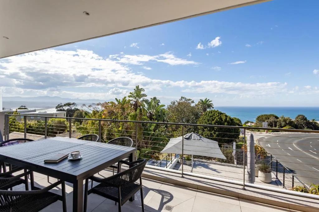 Outdoor dining area with ocean and mountain views from shaded deck