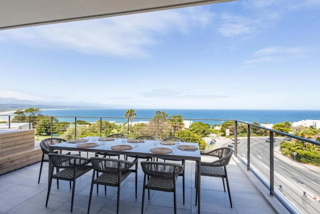 Outdoor dining table with ocean and coastline views from elevated deck