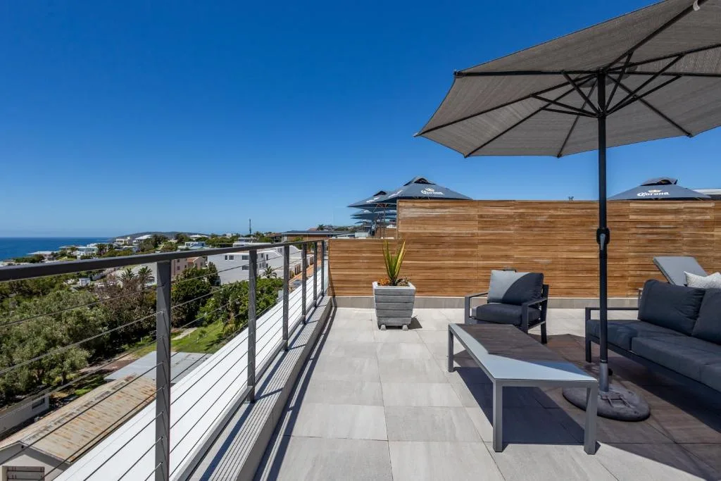 Spacious rooftop deck with ocean views, lounge seating, and umbrellas
