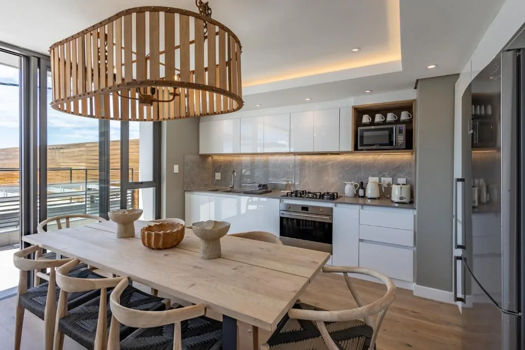 Modern dining table with wooden chairs beneath sculptural pendant light fixture