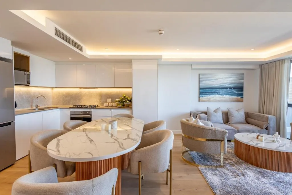 Modern open-plan lounge and dining area with cream furnishings and ocean artwork