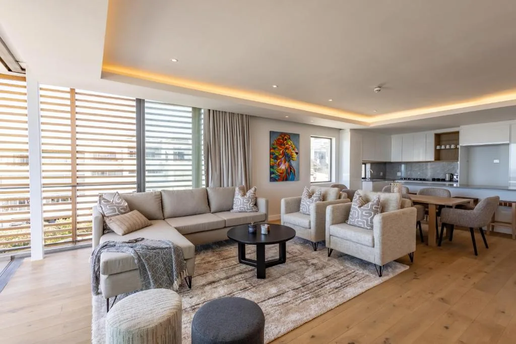 Modern living room with beige sectional sofa, armchairs, and black coffee table