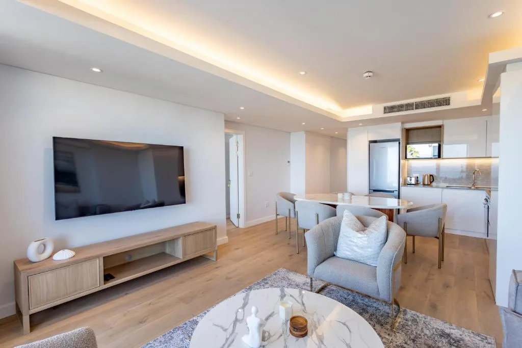 Modern living room with wall-mounted TV, gray armchair, and wooden flooring