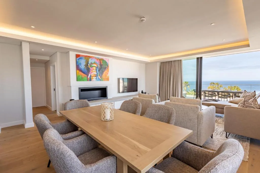 Modern lounge with dining table, fireplace, ocean views through glass doors
