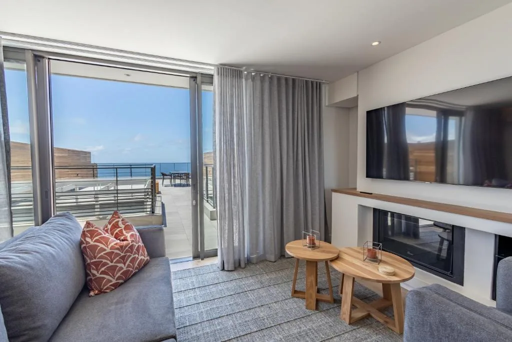 Modern lounge with coastal views, fireplace, and ocean-facing glass doors