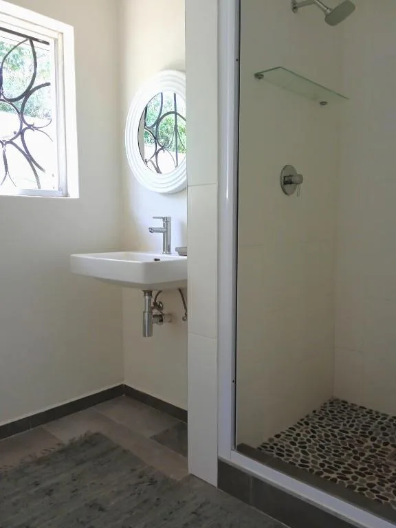 Modern bathroom with wall-mounted sink, circular mirror window, and walk-in shower