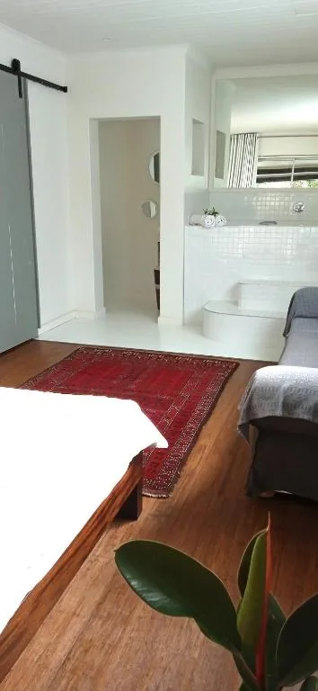 Bedroom with wooden floor, red rug, bed, and ensuite bathroom entrance