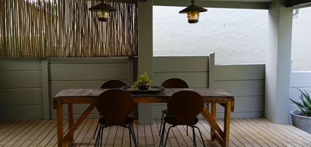 Wooden dining table with black chairs on covered patio deck area