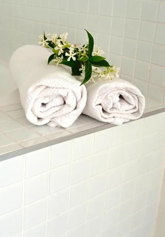 Rolled white towels with fresh flowers on bathroom shelf