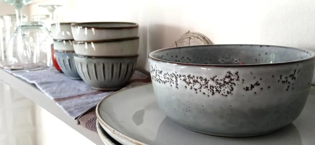 Decorative ceramic bowls and plates arranged on white shelf