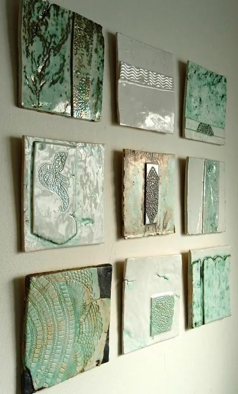 Gallery wall displaying nine framed abstract coastal-inspired artworks in green and cream tones