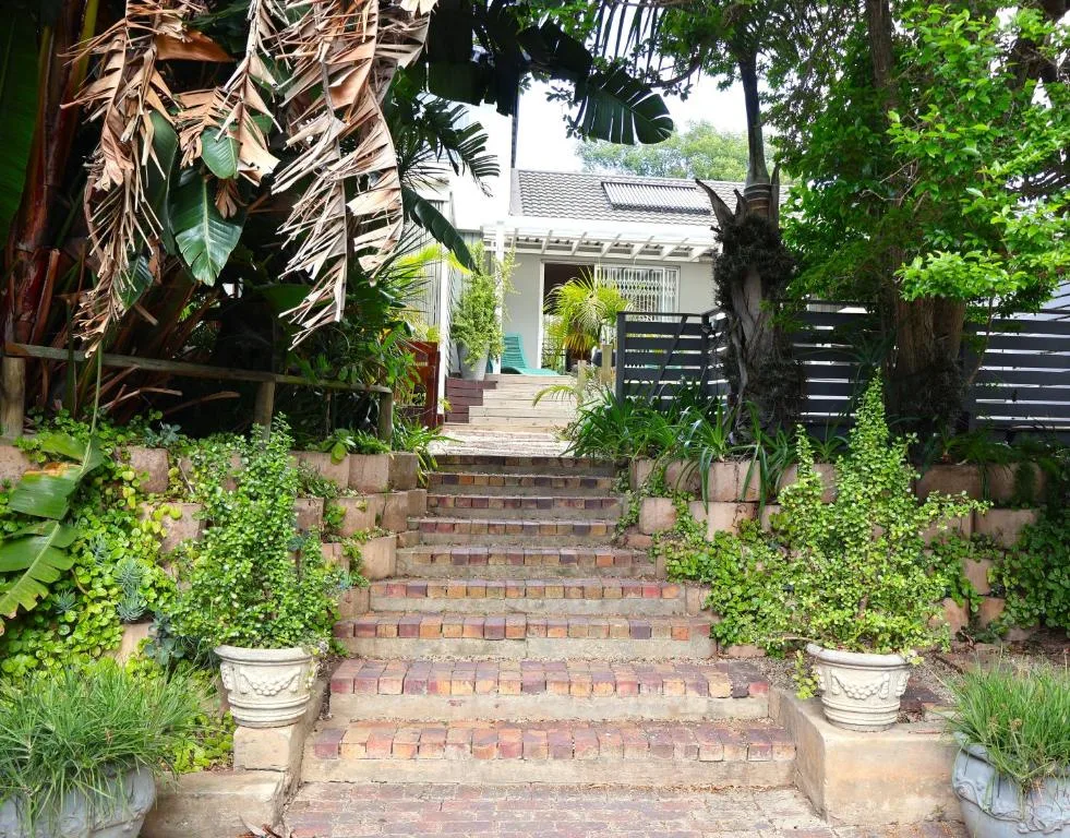 Brick stairway entrance with lush green gardens and cottage facade beyond