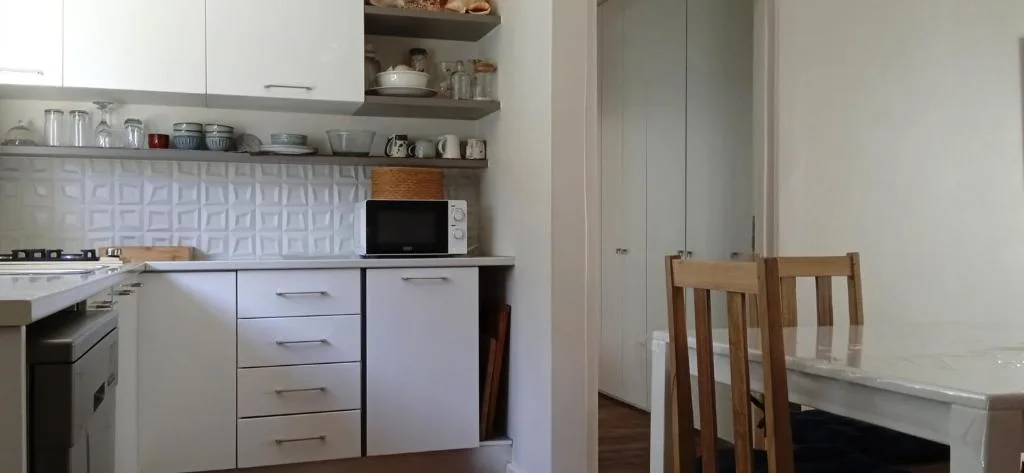 Modern kitchen with white cabinetry, stove, microwave, and open shelving