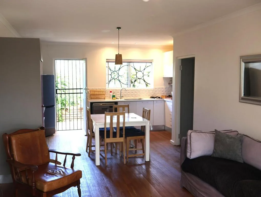 Open-plan living area with sofa, dining table, and kitchen visible