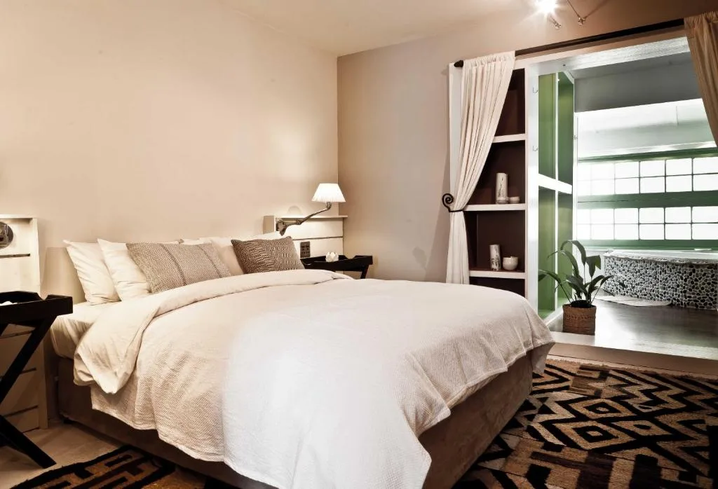 Spacious bedroom with cream bedding, dark wood furniture, and ensuite bathroom access