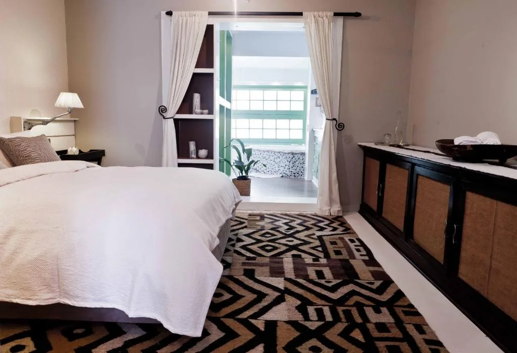 Bright bedroom with white bedding, black dresser, ocean view through glass doors