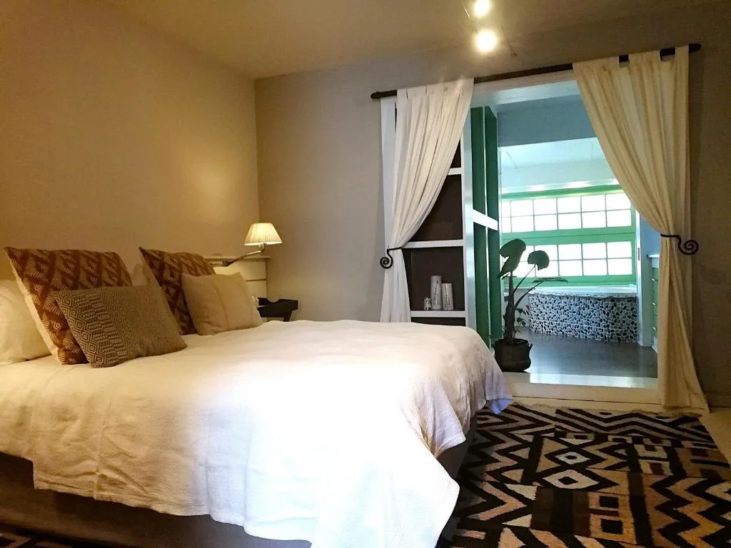 Bright bedroom with white bed, decorative pillows, and green door opening to balcony view