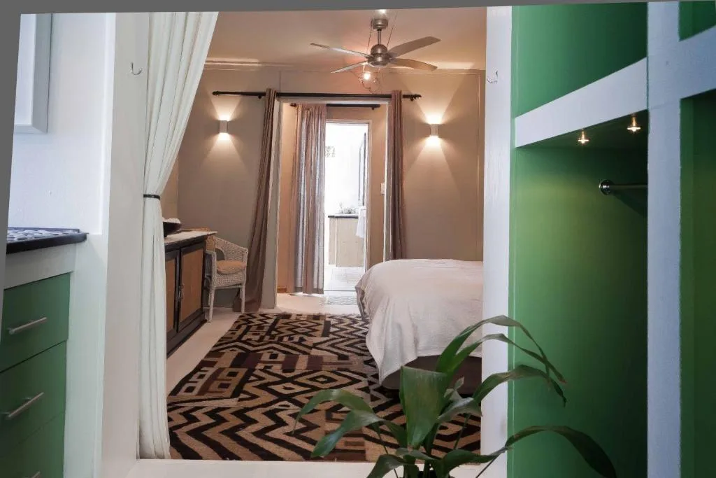 Modern bedroom with queen bed, green accents, geometric patterned rug, deck access