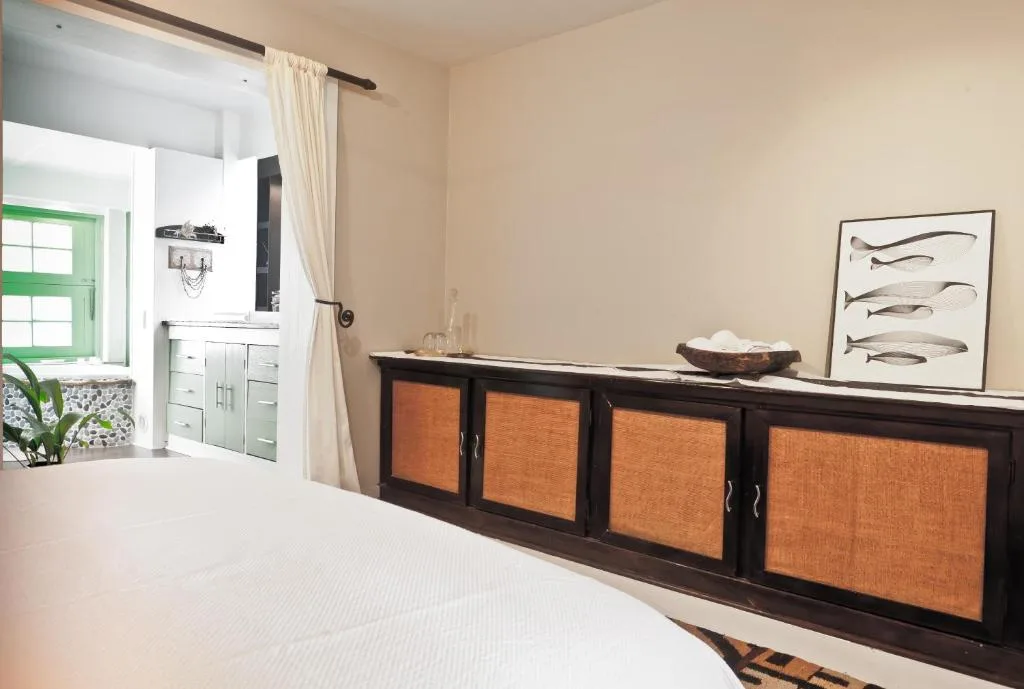 Bright bedroom with white bed, dark wood storage with orange panels, and green window